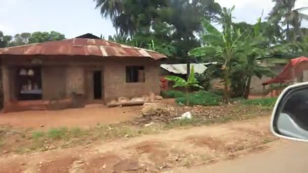 Řízení minulosti slumů a vesnic s zchátralými domy mezi palmami, Afrika — Stock video
