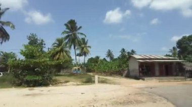 Palmiye ağaçları ve Afrika 'nın arasında harap olmuş evleri olan gecekondu ve köylerin önünden geçmek