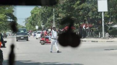 Üniformalı bir Afrikalı polis yolda trafiği düzenliyor.