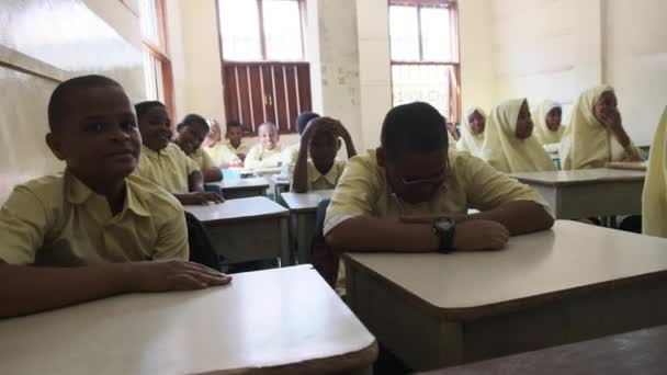 एक अफ्रीकी प्राथमिक स्कूल में बच्चे एक कक्षा, ज़ंज़ीबार में डेस्क पर बैठते हैं — स्टॉक वीडियो
