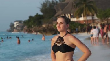 Genç Güzel Kadın Egzotik Sahilde Duruyor ve Uzaklara, Gün batımına Bakıyor