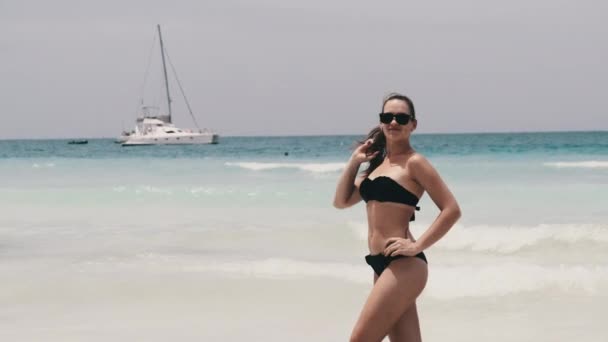 Junge Frau posiert im Bikini am exotischen Strand am türkisfarbenen Ozean von Sansibar