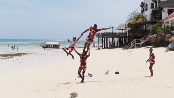 Lokalni Afrykanie wykonują akrobatyczne akrobacje dla turystów na plaży, Zanzibar — Wideo stockowe