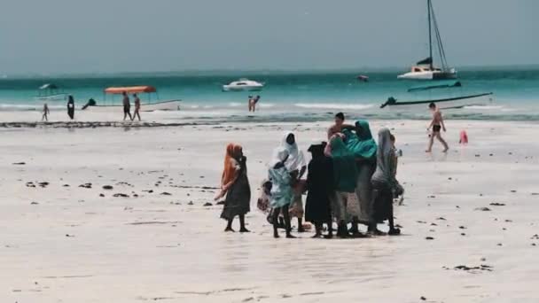 Afrikansk familie af Beggars vandrer i en gruppe på en strand blandt turister, Zanzibar – Stock-video