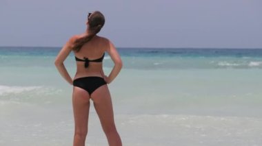Bikini 'deki Genç Kadın Sahilde Duruyor ve Turkuaz Okyanusu' na Bakıyor. Zanzibar