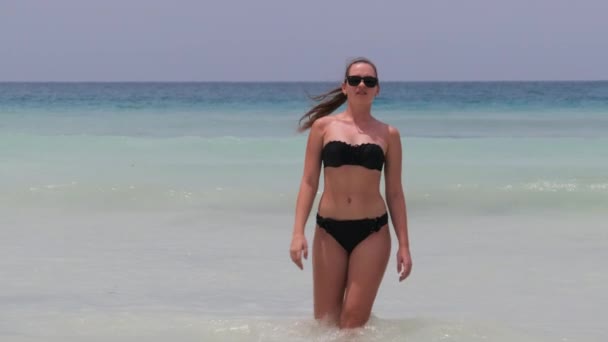 Mujer joven en traje de baño negro camina desde el océano Turquesa en Paradise Beach — Vídeos de Stock