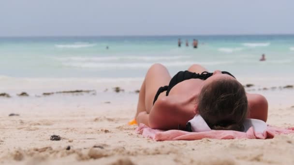 Jonge vrouw zonnebaden op een paradijs zandstrand liggend in zwarte Bikini in de buurt van Ocean — Stockvideo