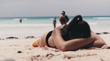 Genç Kadın Cennet 'te güneşleniyor Sandy Plajı' nda Okyanus kıyısında siyah bir Bikini 'de yatıyor