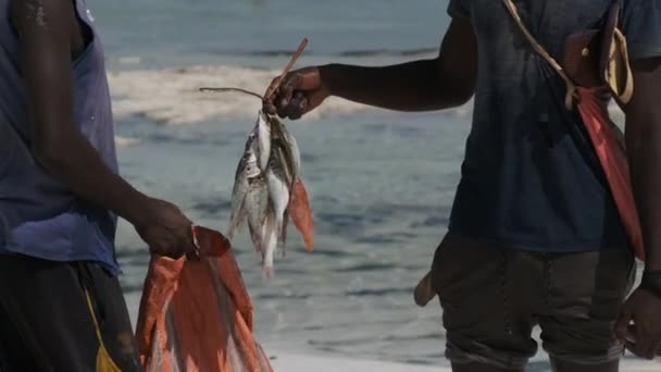 ザンジバルの地元の男に魚の販売の束を持つアフリカの漁師 — ストック動画