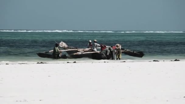 Группа африканских рыбаков в традиционной деревянной лодке возле пляжа, Занзибар — стоковое видео