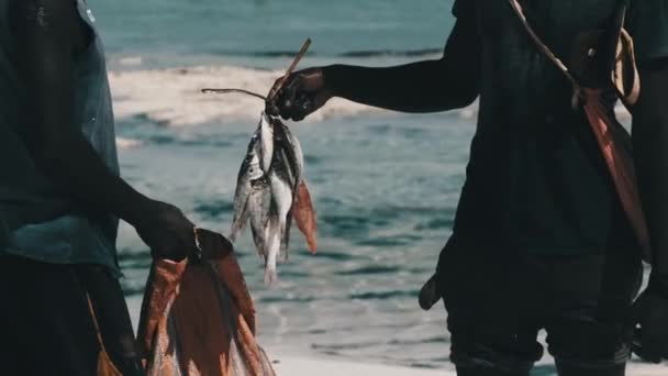 Ein afrikanischer Fischer mit einem Bündel Fisch verkauft Fang an einen Einheimischen auf Sansibar — Stockvideo