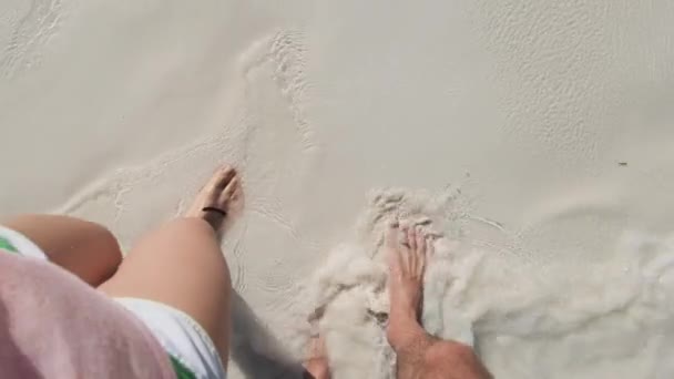 하얀 모래 위를 걷는 한 쌍의 젊은 부부 의발 자국 과해 양의 파도 — 비디오
