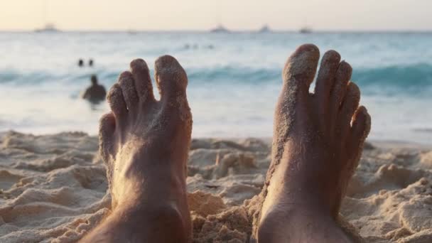 POV Feet of Young Man Leżący na piaszczystej plaży nad oceanem podczas zachodu słońca, Zanzibar — Wideo stockowe