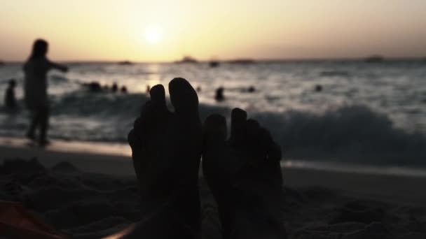 POV Silhouette of Feet of Young Man Lying on Sandy Beach by Ocean During Sunset — Stock Video