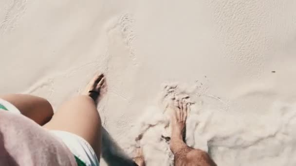 하얀 모래 위를 걷는 한 쌍의 젊은 부부 의발 자국 과해 양의 파도 — 비디오