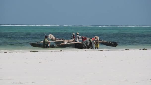 Группа африканских рыбаков в традиционной деревянной лодке возле пляжа, Занзибар — стоковое видео
