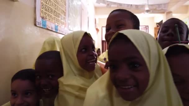 Multitud de niños africanos miran a una cámara dentro de una escuela primaria, Zanzíbar — Vídeo de stock