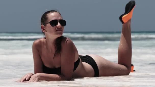 Молода жінка в чорному Бікіні Танс на білому піщаному пляжі Раю лежить біля океану — стокове відео