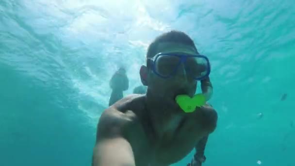 Jovem em uma máscara com um snorkel mergulha sob a água e filma-se — Vídeo de Stock