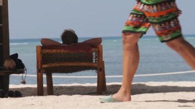 Okyanus kıyısındaki Şemsiye Sahili 'nin Gölgesinde Güneş Yatağında Yatan Turist. Zanzibar