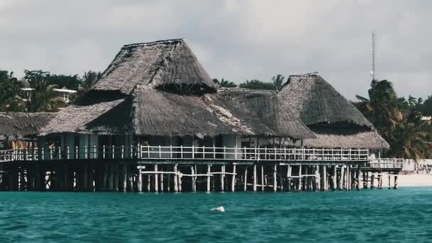 海の上の木製のポールに茅葺き屋根のアフリカ料理レストラン。ザンジバル — ストック動画