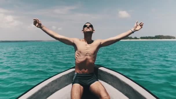 Молодой успешный человек с протянутыми руками наслаждается на палубе лодки у океана — стоковое видео