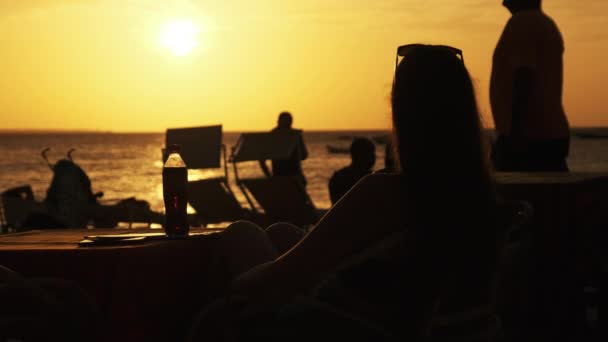 Silhouette Giovane donna seduta a tavola sulla spiaggia e guardando il tramonto di Ocean — Video Stock
