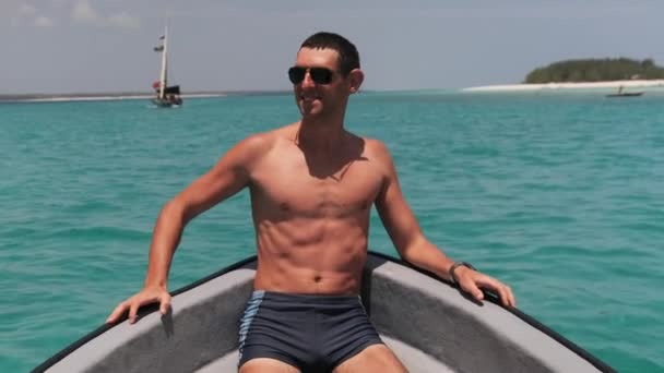 Młody człowiek w okularach przeciwsłonecznych cieszący się na łuku łodzi pływającej nad oceanem — Wideo stockowe