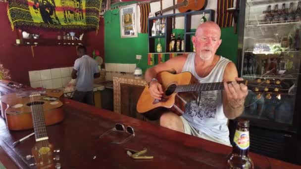 Een oudere Amerikaan speelt gitaar in een lokale Afrikaanse bar buiten, Zanzibar — Stockvideo