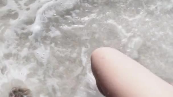 Punto de vista de las piernas de una mujer joven caminando por la arena blanca y olas de surf de la orilla del mar — Vídeos de Stock