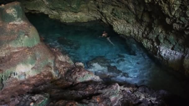 Giovane donna nuota in un fiume sotterraneo in grotta con acqua dolce tra le scogliere — Video Stock