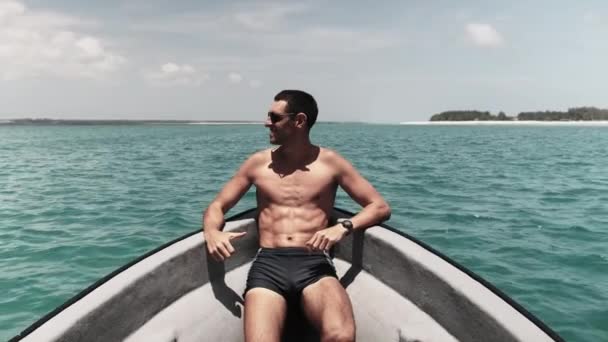 Mladý úspěšný muž v slunečních brýlích těší na přídi lodi plovoucí u oceánu — Stock video