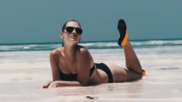 Jeune femme en bikini noir bronzage sur une plage de sable blanc Paradise se trouve près de l'océan — Video