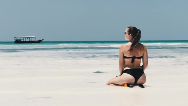 Νεαρή γυναίκα σε μαύρο μπικίνι Tans στο Lotus Pose στον παράδεισο Sandy Beach από τον ωκεανό — Αρχείο Βίντεο