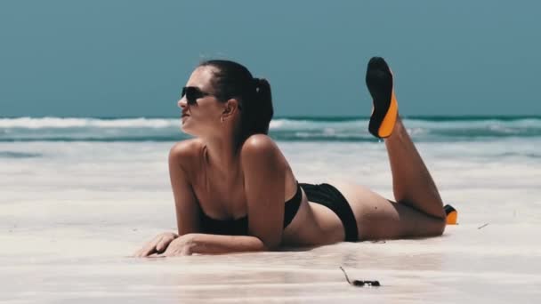 Jeune femme en bikini noir bronzage sur une plage de sable blanc Paradise se trouve près de l'océan — Video