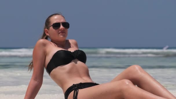 Young Woman in Black Bikini Tans on a Paradise White Sandy Beach encontra-se por Ocean — Vídeo de Stock