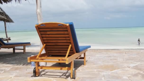 Stand per lettini vuoti di fronte all'oceano sulla spiaggia Paradise, Zanzibar, Vista posteriore — Video Stock