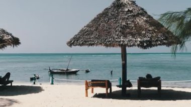 Ocean, Zanzibar 'dan Thatched Şemsiyeleri ve Sun Loungers with Man on Sandy Beach
