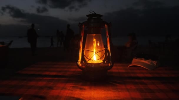 ロマンチックなキャンドルライトディナーオーシャンビーチの夜、ケロシンランプテーブルの上に点灯 — ストック動画