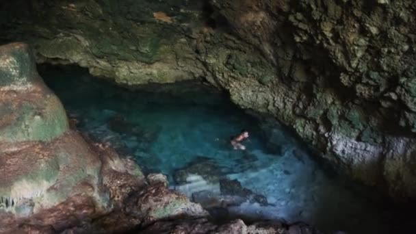 Giovane donna nuota in un fiume sotterraneo in grotta con acqua dolce tra le scogliere — Video Stock