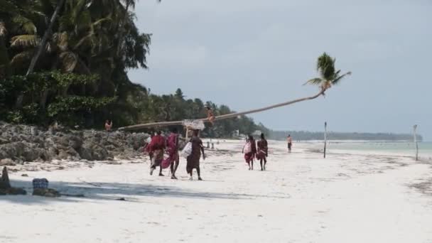 Maasai Walk Längs den tropiska stranden vid havet bland turister i Zanzibar Island — Stockvideo