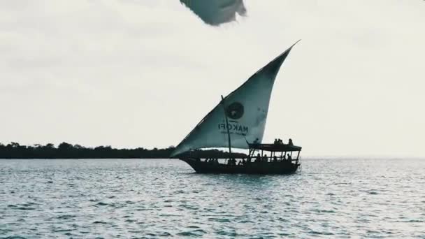 Tradiční africký člun Dhow s turisty plave pod otevřenou plachtou u oceánu — Stock video