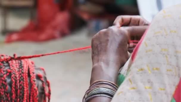 Mujer africana tejiendo trenzas africanas con Kanekalon rojo al aire libre, Zanzíbar África — Vídeos de Stock