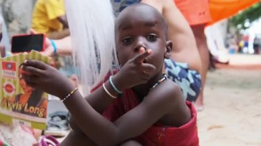 Yerli Brezilyalı Açlıktan ölen Afrikalı Çocuk Kamera ve El sallayan Eller 'e bakıyor, Zanzibar