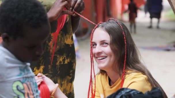 Afrikanerin webt afrikanische Zöpfe mit rotem Kanekalon Outdoor, Sansibar Afrika — Stockvideo