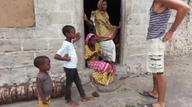 Beyaz bir turist, Zanzibar köyündeki yerel Afrikalı insanlarla iletişim kuruyor.