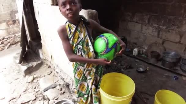 Afrikalı bir kız, Zanzibar adındaki bir Afrika köyündeki gecekondu mahallesinde elinde top tutuyor. — Stok video