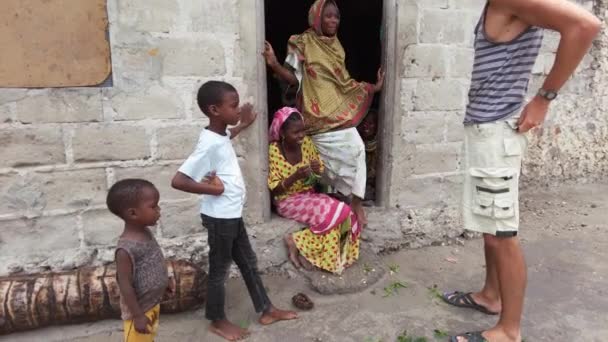 En vit turist kommunicerar med lokalbefolkningen i byn, Zanzibar — Stockvideo