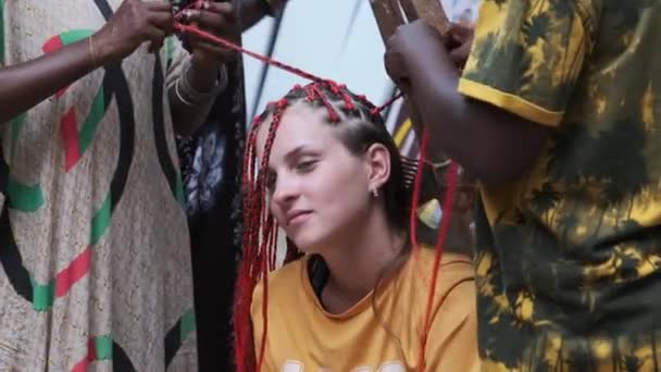 Proceso de tejer trenzas africanas con Kanekalon rojo al aire libre, Zanzíbar, África — Vídeos de Stock