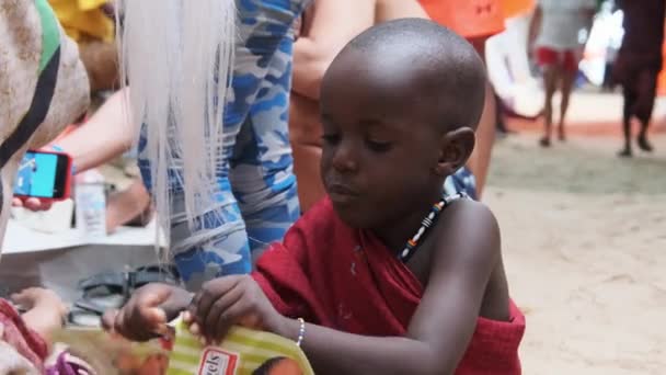 Місцеві африканські голодні діти їдять папір на вулиці серед людей, Занзібар, Африка — стокове відео
